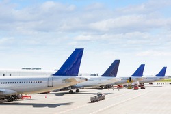 Tails of some airplanes at airport during boarding operations. They are four planes on a sunny day, with a blue sky. Travel and transportation concepts.