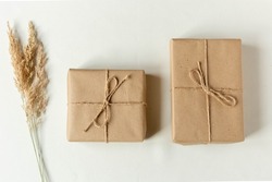 Two handmade Christmas presents . Gifts wrapped in craft paper and rope bow with pine tree branches as background.