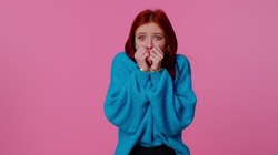 Stressed depressed teen student girl 20s years old in blue sweater expresses his fear and waves his hands away from danger, waving no. Scared fearful young woman isolated on pink wall background