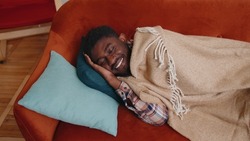 Candid casual african american young man sleeping quietly in bedroom at home. Happy adult guy smiling, lying on bed, sleeping on a comfortable sofa and pillow, resting peacefully. Healthy sleep alone