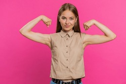 I am strong and independent. Young woman showing biceps and looking confident, feeling power strength to fight for rights, energy to gain success win. Girl isolated alone on pink studio background