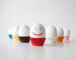 Eggs positioned in a triangle position on white background, positive concept idea with smiley face for egg's day, selective focus effect