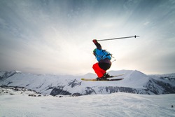Skier skiing on fresh white snow with ski slope on Sunny winter day