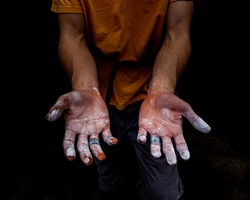 Moody close-up of a Rock Climber's hands taped up and covered in chalk after an intense coastal climbing session.