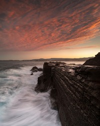 Long exposure photo of a rock wall hit by large waves, Australia
