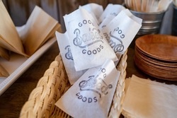 white paper bags with Baked Goods stamped on in a basket on a table