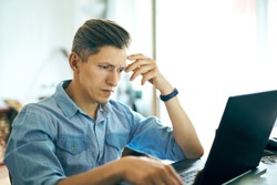 handsome man working using laptop computer at office. man texting, looking at laptop screen and showing reverie and concentration. Concept of resolving problems, management, investing in startups