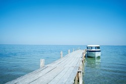 Beautiful paradise seascape, white boat in turquoise clear waters near wooden beach pier