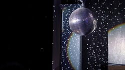 The disco ball is spinning at the party. Light effects of the starry sky, reflections in a mirror ball. Stage light in a nightclub or concert. Blue and white.