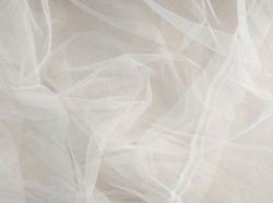 White mosquito net fabric texture with folds. Wavy chiffon background. Full frame of crumpled white cloth material texture. Abstract white net fabric pattern for patterns and designs.