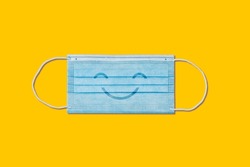 Happy smiling medical face mask on yellow background.