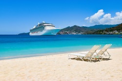 Cruise ship in Caribbean Sea with beach chairs on white sandy beach.
Summer travel concept.