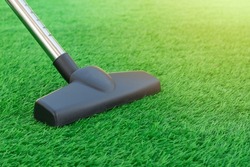 Selective focus of a vacuum cleaner on a sheet of artificial turf. Lawn care and maintenance. Easy to clean artificial greenery roll