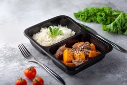 a dish in a black disposable container from catering on a concrete background, dietary catering, ready meals with you, healthy food