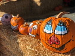 Funny pumpkin faces. Painted pumpkins placed on hay bales at Speer Family Farms Pumpkin Patch.