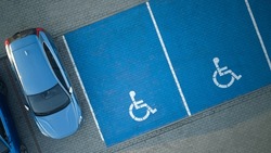 Outdoor car parking with handicapped symbol icon. Parking places reserved for disabled person. Aerial drone view.