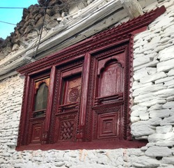 Old ancient door burgundy color with decorative ornaments in stone building in Mustang kingdom, Nepal. Stone house in Marpha village, Lower Mustang, northern Nepal. Traditional tibetan architecture.