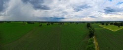 Aerial panoramic view of dramatic storm clouds over farm fields. Country landscape of the bad weather. Very windy weather. Plain field against the background of dark sky and clouds forming. High