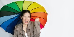 Asian beautiful  woman holding a colorful umbrella looking up to see raining and laughing with feeling win and success