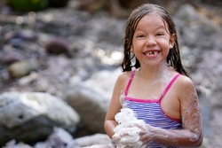            Beautiful happy girl enjoying a good bath in the river outdoors smiling and cheerful                    