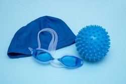 swimming cap, goggles and ball for playing in the water on a blue background.
