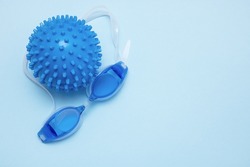 swimming goggles and a ball for playing in the water on a blue background with copy space