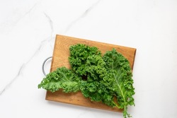 Top view of bunch green fresh kale cutting board on light surface copy space