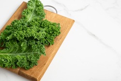 Top view of bunch green fresh kale cutting board on light surface copy space vegan concept