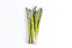 Bunch of raw asparagus stems isolated on white. Edible Asparagus Officinalis sprouts laid on paper textured background. Close up, copy space, top view, flat lay.