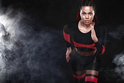 Strong athletic woman sprinter, running on black background wearing in the sportswear. Fitness and sport motivation. Runner concept.