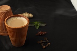Kulhad Chai is a tea beverage made in India, milk tea with aromatic herbs and spices, Cup of tea on black background Premium Photo, masala tea in kulhad brown mud cup with dark background