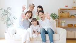 three generation asian family waving hands in the living room