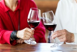 closeup hands of middle aged asian couple toasting with red wine
