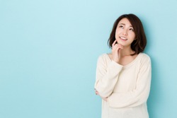 attractive asian woman thinking isolated on blue background