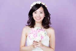 portrait of attractive asian woman wearing wedding dress isolated on purple background