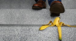 Accident in Daily Life Concept. Man Stepping Down Stair on a Banana Peel. Insurance or Business Metaphor
