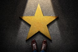 Success in Business or Personal Talent Concept. Top View of Business Person in Working Shoes Standing in front of a Golden Star. Light Shining on the Dark Cement Floor