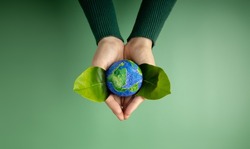 World Earth Day Concept. Green Energy, ESG, Renewable and Sustainable Resources. Environmental and Ecology Care. Hands of Person  Embracing Green Leaf and Craft Globe