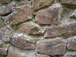 Ancient stonework. The stones are reinforced with old mortar. Uneven masonry ancient wall. Gray