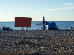 Blank sign on the beach. Mocap. Place for an inscription on the seashore. End of the season. On the Sunset. Beach vacation. Resort by the sea.