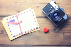 letter, camera and heart on wooden table background
