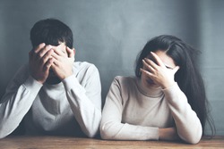 sad young couple sitting in table on dark background