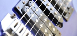 Electric guitar bridge, strings and pickup. Detail close-up view of guitar pickup in blue color. Music instrument
