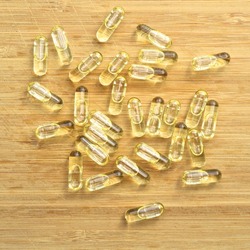 Yellow fish oil oval tablet pills on bamboo cutting board, medical oval pills tablets