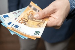 Well dressed man holding in the hand or giving bunch of money, euro banknotes, European Union paper currency.