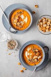 Vegetarian autumn pumpkin and carrot soup with cream, seeds and toasts. Autumn and winter healthy food concept.