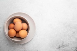 Brown chicken eggs in plate on light background. Concept farm products and natural nutrition. Top view, copy space or empty place for text.
