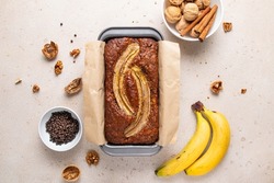 Traditional American homemade banana bread with chopped walnuts, chocolate chips and cinnamon in loaf pan on light background. Fruit cake. Healthy vegan desserts concept.