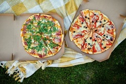 Two pizzas in the food carton on the grass, picnic concept, top view, copy space. Take away food, fastwood, italian pizza outdoor.