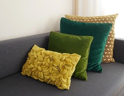 Selection of stylish green and yellow pillows on modern grey sofa. High quality photo